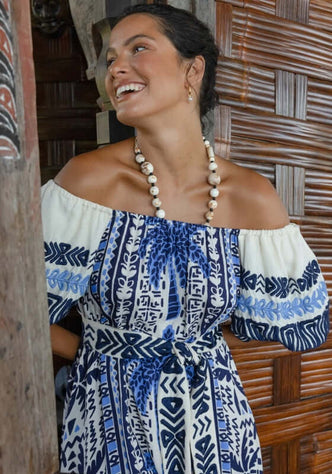 Mya Dress by Miss June, featuring a smiling model wearing a bohemian chic dress with Aztec and palm tree patterns.