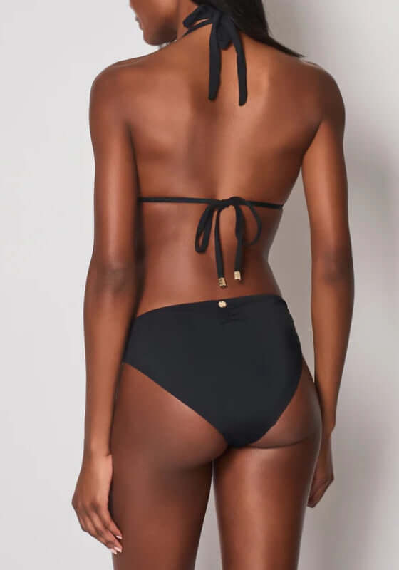 Maia Bikini Bottoms Black by Naia Beach, showcasing a model wearing a stylish black bikini bottom from the back.