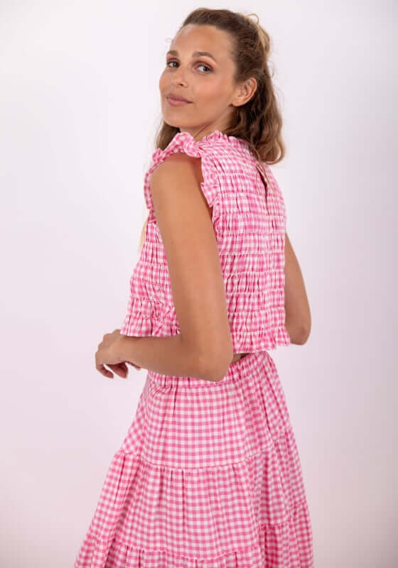 Malone Top Gingham Pink by Sundress, model wearing a stylish gingham top with ruffle cap sleeves.