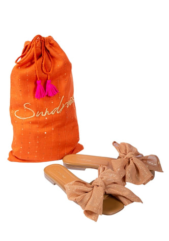 Amour Sandals Terracotta by Sundress, featuring terracotta sandals with large bows beside a matching orange bag.