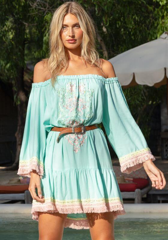 Azra Beach Dress by Miss June, elegant blue dress with off-shoulder neckline, long sleeves, and fringe hem detail.