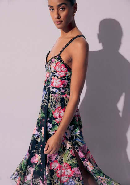 Iraso Long Dress Black Botanical by Charo Ruiz, featuring a floral design, V-neckline, and spaghetti straps for a feminine look.
