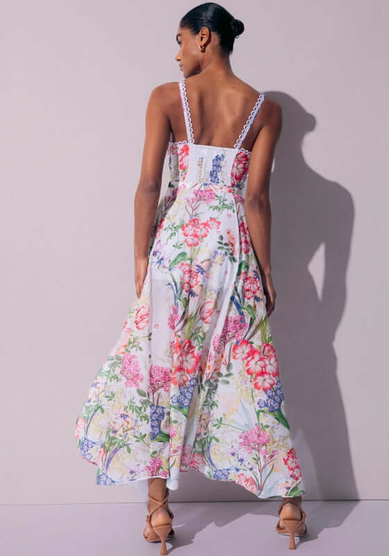 Iraso Long Dress White Botanical by Charo Ruiz showing a model from the back in a floral design with spaghetti straps.