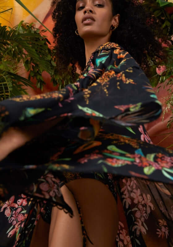 Ivet Kaftan Black Fresca by Charo Ruiz featuring a model in a floral print kaftan against vibrant tropical background.