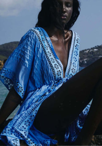 Maisie Kaftan Blue by Charo Ruiz, showcasing a model in a vibrant washed blue kaftan by the beach.
