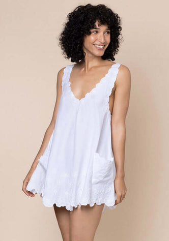 Low Back Dress White by Juliet Dunn, featuring a model in a lightweight white cotton mini dress with scalloped trim.