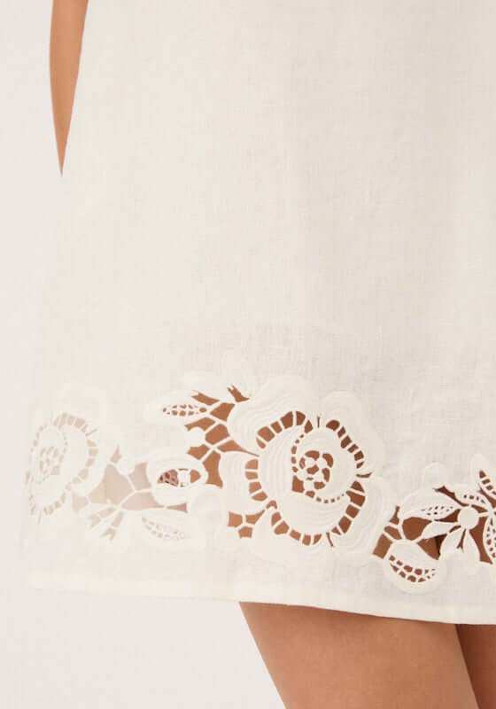 Holiday Mini Dress Gardenia by Peony featuring a delicate floral cutout hem design on a crisp white fabric.