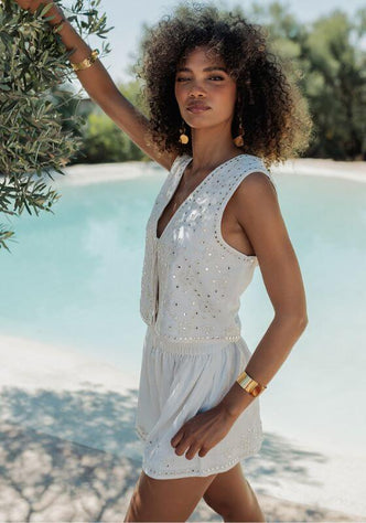 Sicilia Vest White by Piti Cuiti worn by a model, showcasing a tie-front design and mirrored details by a pool.
