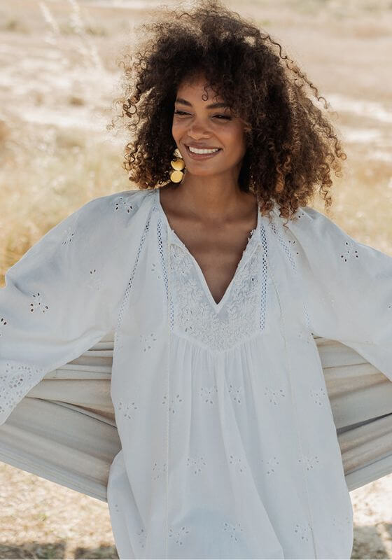 Santorini Dress White by Piti Cuiti model wearing elegant short dress with flare sleeves and cutout details outdoors.