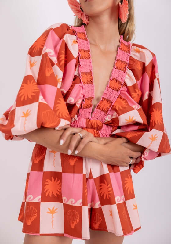 Alicia Jumpsuit Maritius by Sundress, featuring kimono sleeves and a flared bottom in vibrant pink and orange print.