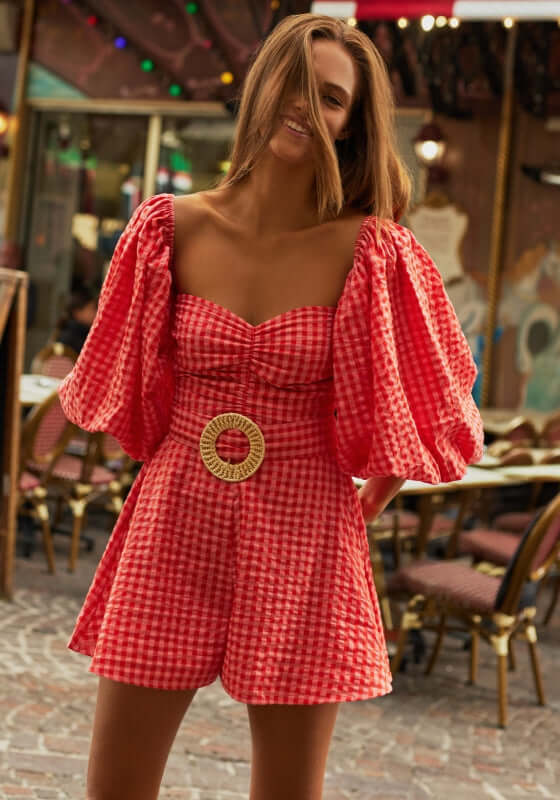 Emilia Jumpsuit Gingham Coral by Sundress features a flattering sweetheart neckline and dramatic sleeves.