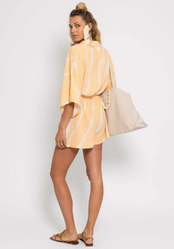 Emma Jumpsuit by Sundress, featuring a relaxed tie dye design with short wide sleeves and a stylish beach bag.