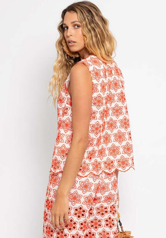Bao Top Red Eyelet by Sundress modeled by a woman with wavy hair, showcasing its elegant floral pattern from the back.