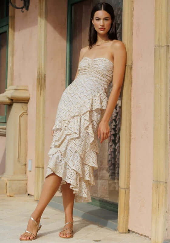 Flavie Dress White by Sundress. Model wearing a strapless white dress with gold embroidery and asymmetric tiered ruffles.