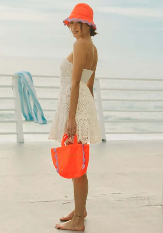 Ivana Dress White by Sundress, a model in a strapless summer dress with pineapple eyelet details and a flounce hem.