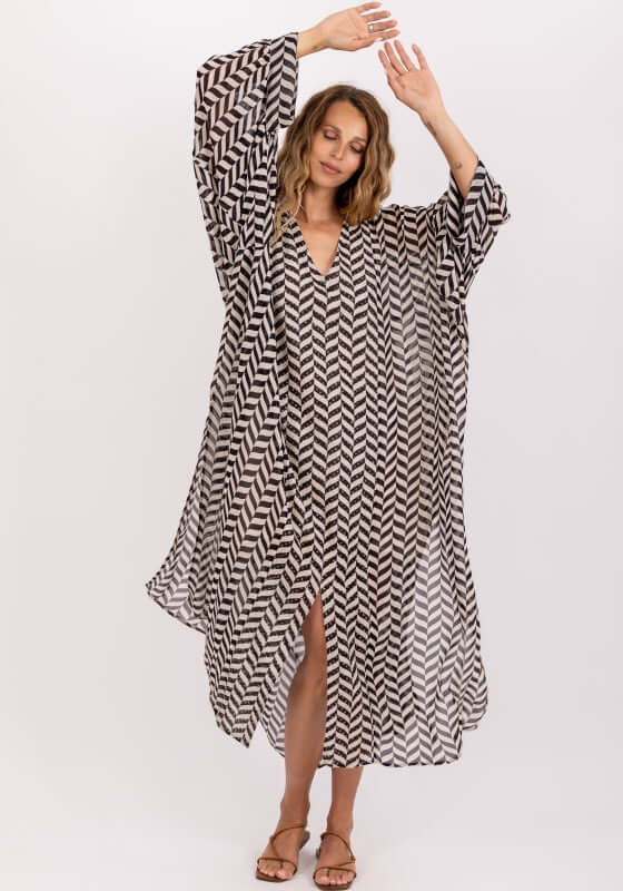 Louli Kaftan by Sundress, stylish black and white caftan with slits and V neckline, model wearing it and posing.