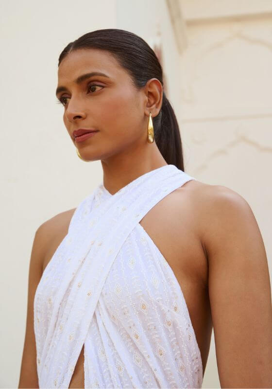Suzie Tulum White Dress by Sundress, featuring a model showcasing the dress's crossover design and sequined fabric.