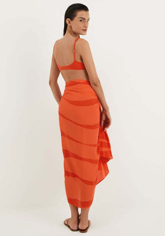 Cherie Sarong by Vix showcases a model wearing an elegant orange sarong, perfect for beach days.