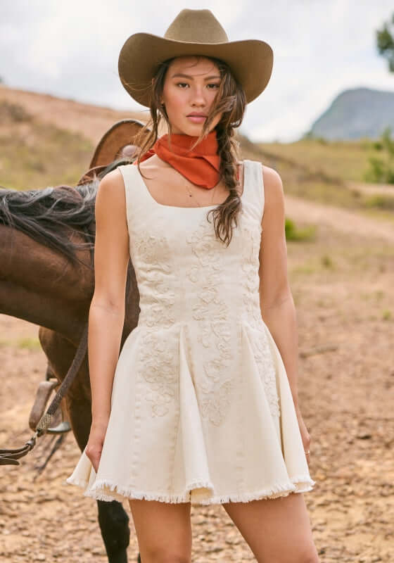 Kristen Sereia Dress by Agua Bendita on model, featuring structured bodice and pleated skirt with floral details.