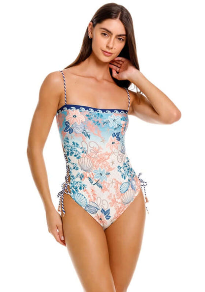 Mariel Sereia Swimsuit by Agua Bendita, featuring lace-up side details and floral patterns on a model at the beach.
