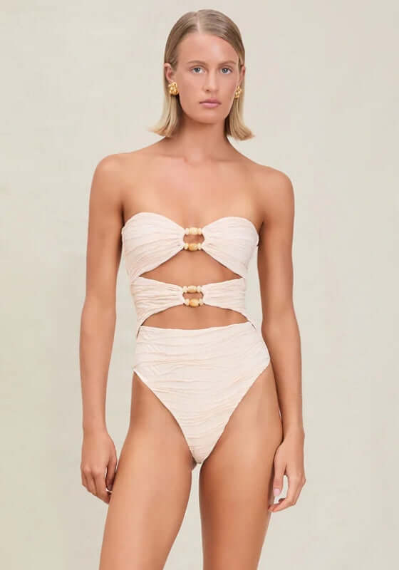 Amii Swimsuit Pebble by Devon Windsor, soft cream one-piece with cut-out front and ring details, perfect for beach days.