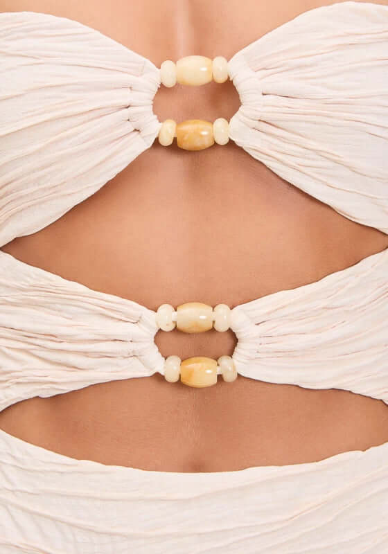 Amii Swimsuit Pebble by Devon Windsor featuring a close-up of the cut-out front and decorative ring details.