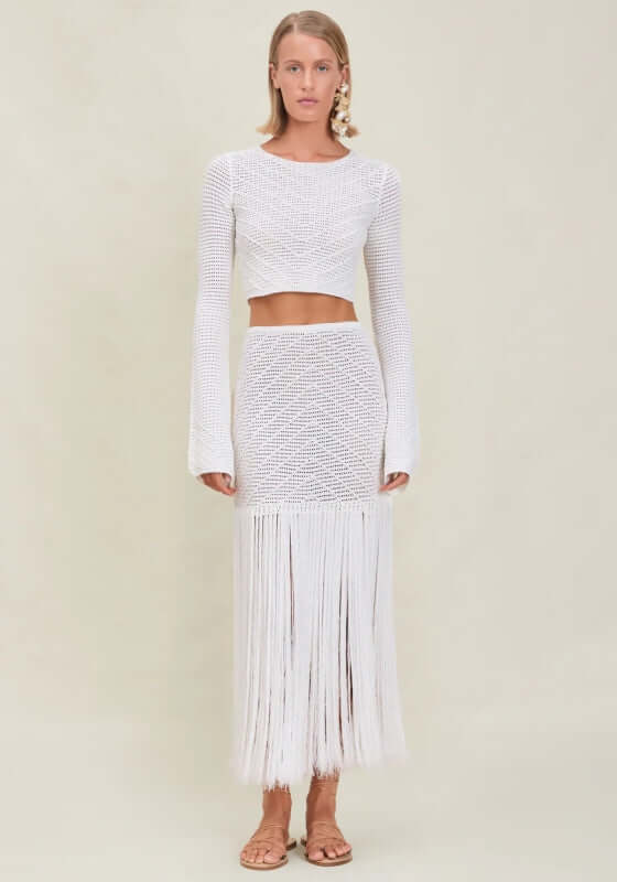 Edna Skirt Dove by Devon Windsor, featuring a long tassel hem and lightweight knit fabric in a stylish beach setting.