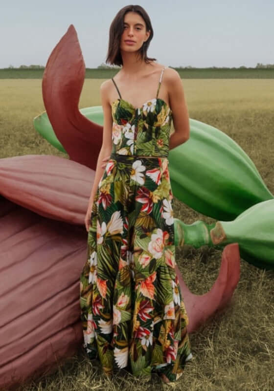 Botanical Forest Midi Skirt by Farm Rio, showcasing a model in a lush floral dress against oversized nature-inspired sculptures.