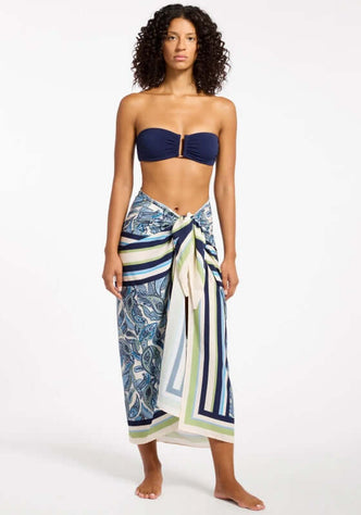 Oasis Paisley Sarong Ink by Jets, showcasing a woman in a paisley sarong with navy and green colors, perfect for beachwear.