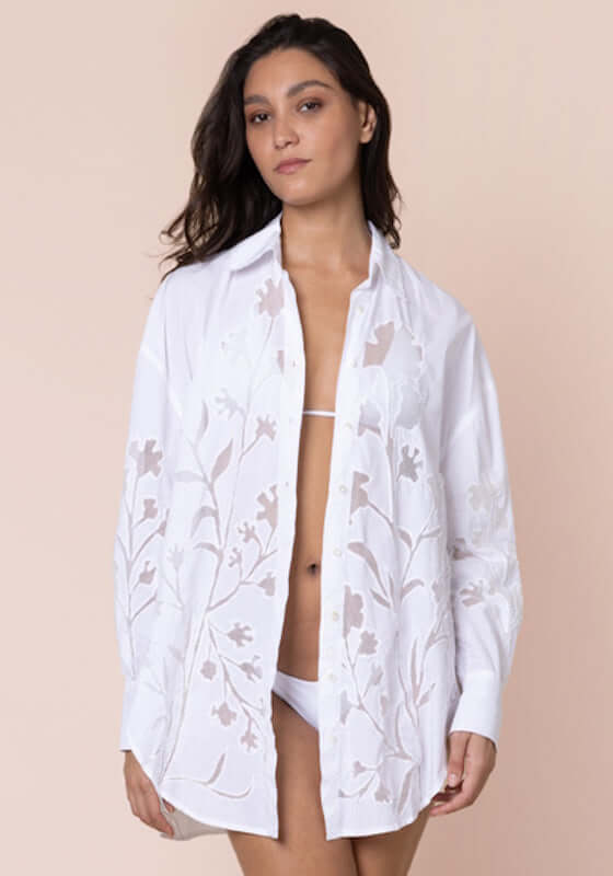 Floral Cutwork Shirt White by Juliet Dunn, model wearing striking white shirt with floral cutwork detailing over white swimwear.