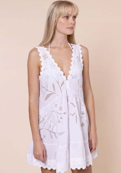 Floral Cutwork V Neck Mini Dress White by Juliet Dunn. Model wearing a white mini dress with floral cutwork and scalloped hem.