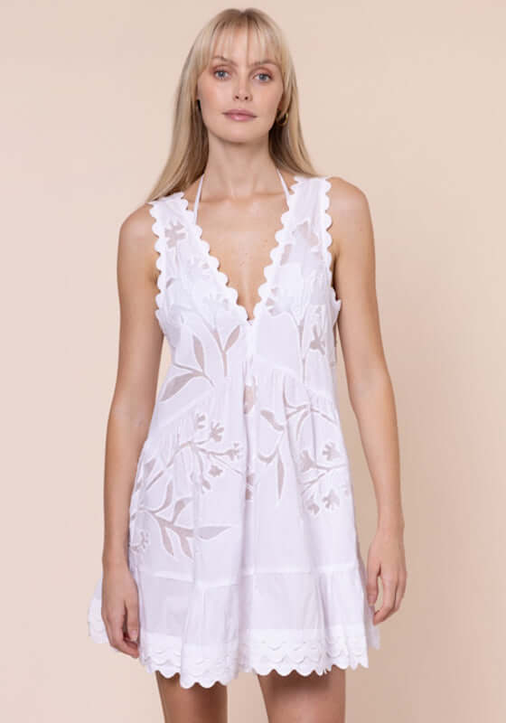 Floral Cutwork V Neck Mini Dress White by Juliet Dunn; model wearing a white mini dress with floral cutwork and a plunging V neckline.