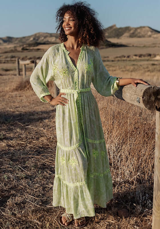 Sahara Long Dress Neon Green by Piti Cuiti, featuring a flattering V-neckline and balloon sleeves in a scenic outdoor setting.