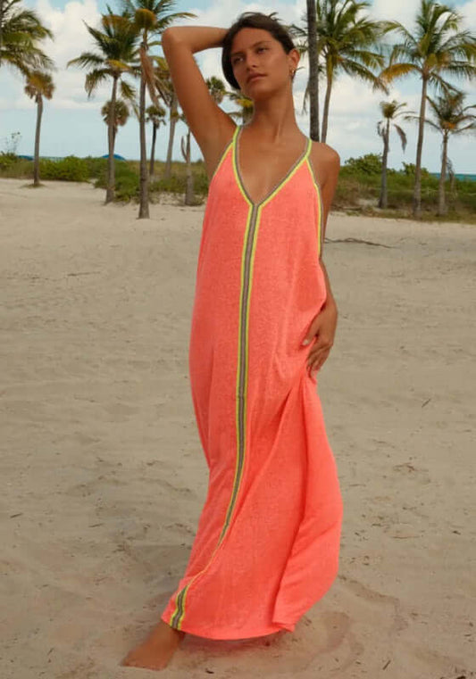 Inca Maxi Sun Dress Watermelon by Pitusa, showcasing a model on the beach in a vibrant coral dress with stylish design details.