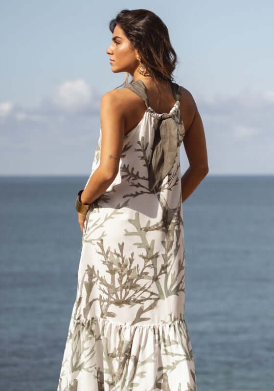 Chloe Dress Garden Taupe by Sole Lisboa, featuring a loose fit and halter neckline with a muted garden taupe print against a coastal backdrop.