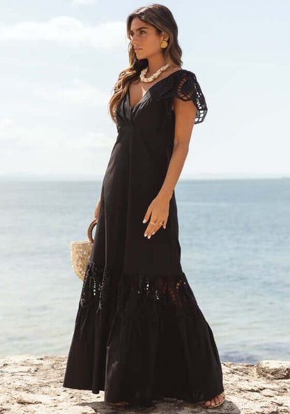Copacabana Dress Black by Sole Lisboa, featuring a V-neckline and eyelet cutout details by the beach.