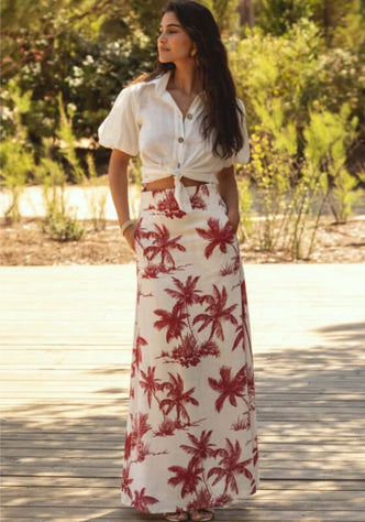 Mykonos Skirt Palm Muse Red by Sole Lisboa worn outdoors, featuring red palm motifs on a white background.