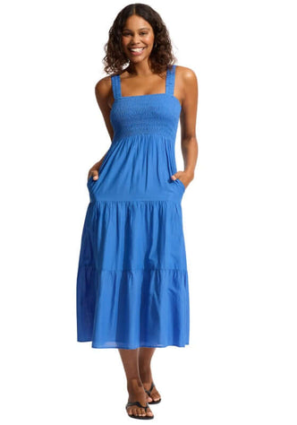 Faithful Midi Dress Sapphire by Seafolly, showing a woman in a blue smocked dress with tiered skirt and pockets.