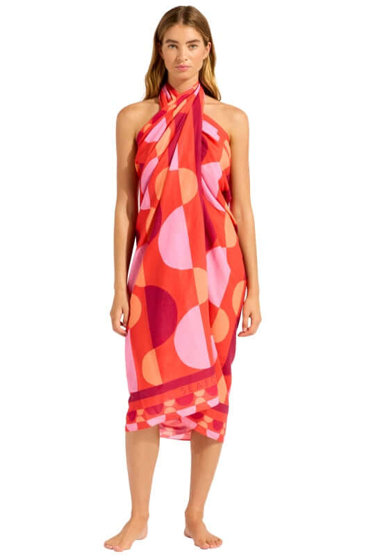 Sorrento Flame Sarong by Seafolly worn by a model, showcasing vibrant geometric patterns in warm flame tones.