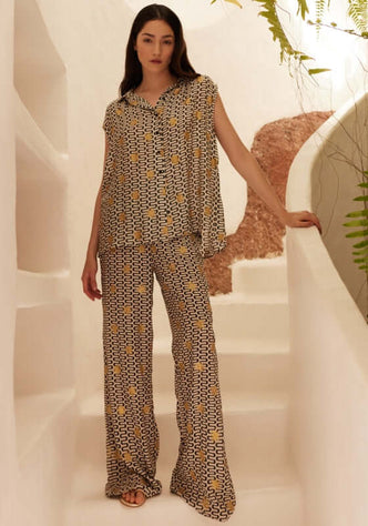 Assia Blouse Symi Black by Sundress, model wearing a sleeveless blouse with a swirly print and gold suns, stylish and relaxed fit.