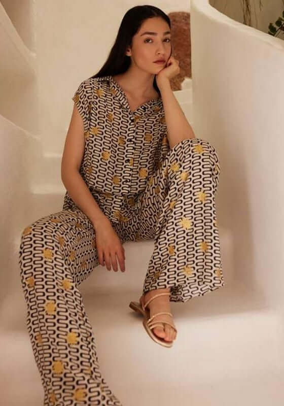 Assia Blouse Symi Black by Sundress, featuring a model in a stylish swirly print outfit with gold suns.