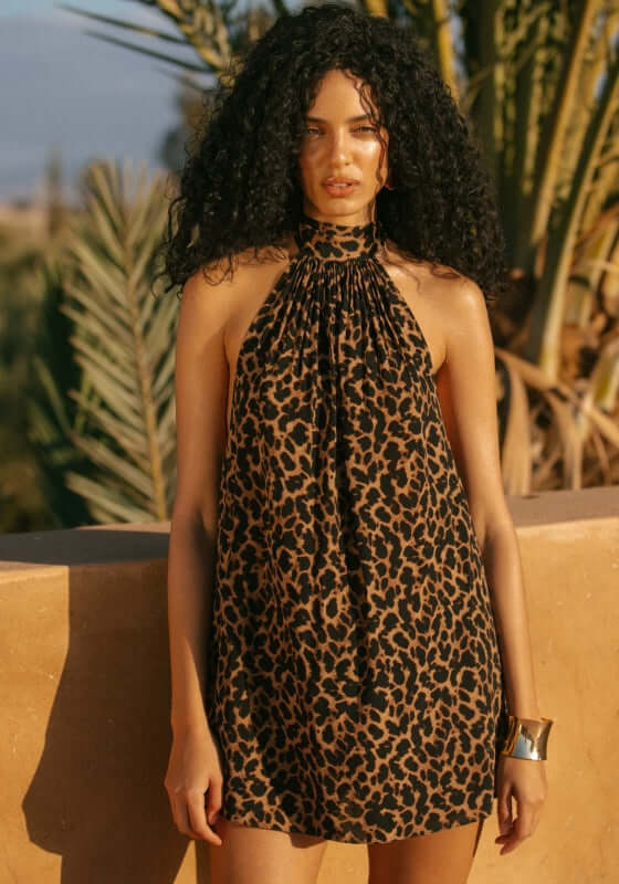 Ibiza Dress Leopard by Away That Day, model wearing a breezy leopard print dress against a sunny backdrop.
