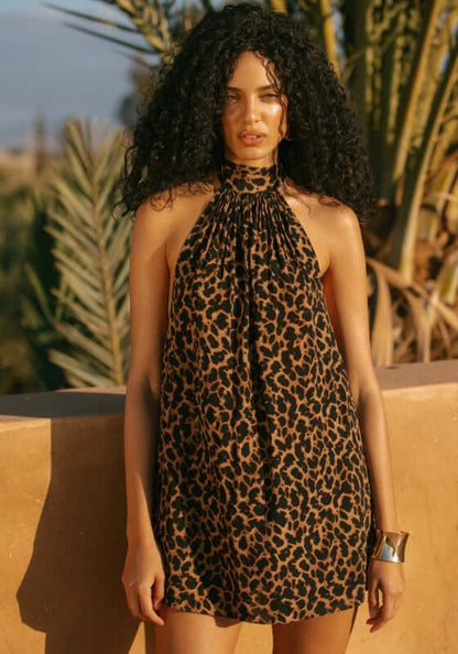 Ibiza Dress Leopard by Away That Day, model wearing a breezy leopard print dress against a sunny backdrop.