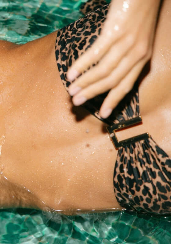 Taormina Bikini Top Leopard by Away That Day, featuring a leopard print design and stylish clasp detail in water.