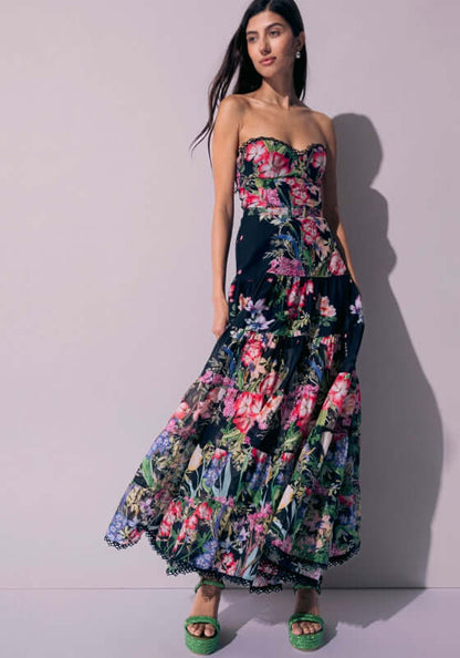 Danny Long Dress Black Botanical by Charo Ruiz, showcasing a model in a floral strapless maxi dress with a fitted bodice.