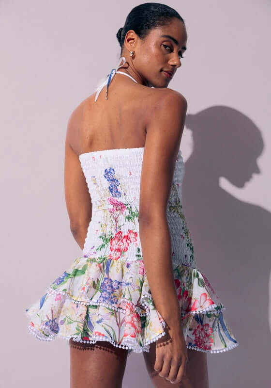 Cusia White Botanical by Charo Ruiz featuring a model in a floral dress with ruffled details and a smocked bodice.