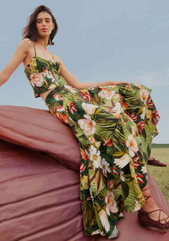 Botanical Forest Midi Skirt by Farm Rio, model sits on a giant flower, showcasing the flowing, floral-patterned design.
