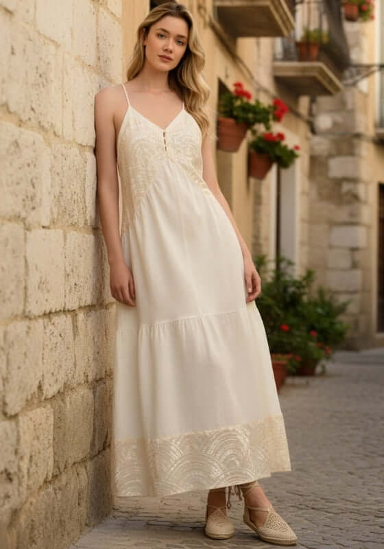 Triangle Strappy Maxi Dress Natural by Greek Archaic Kori, featuring a model in a elegant white cotton maxi dress with gold embroidery.