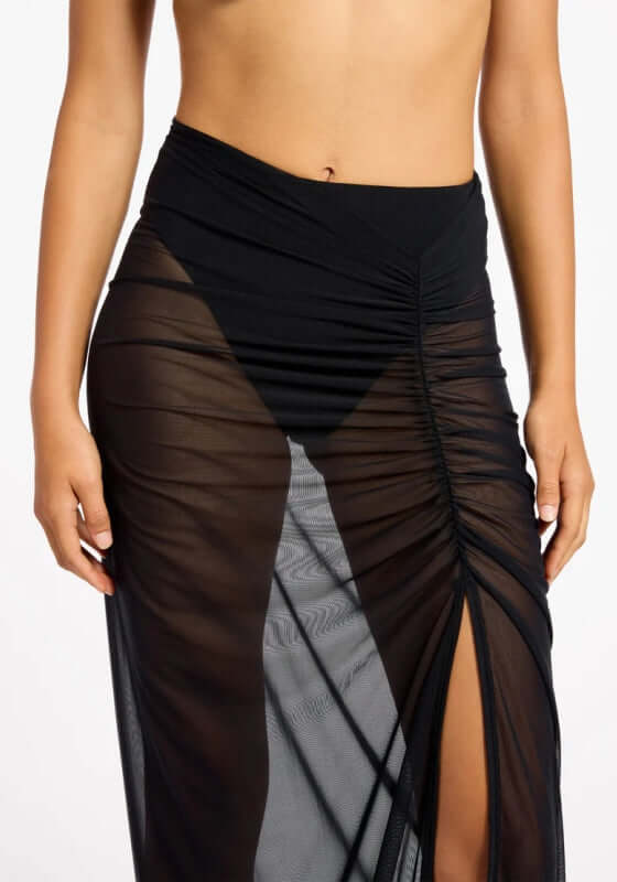 Jetset Lure Mesh Skirt by Jets Swimwear, showcasing sheer black fabric with side ruching and a high slit.
