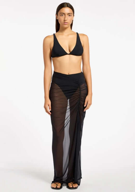 Jetset Lure Mesh Skirt by Jets Swimwear, model wearing a black sheer maxi skirt with side ruching.